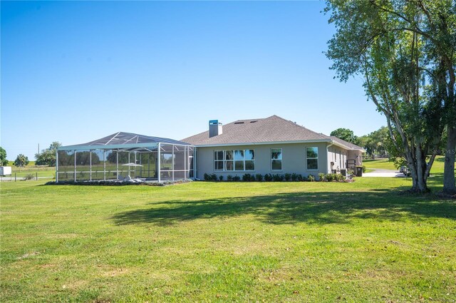 back of house with a lanai and a yard