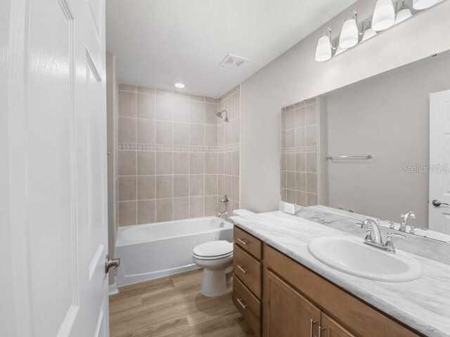 full bathroom featuring tiled shower / bath, toilet, vanity, and hardwood / wood-style flooring