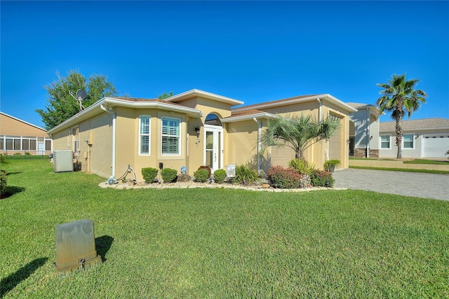 view of front of property with a garage, a front yard, and central AC unit