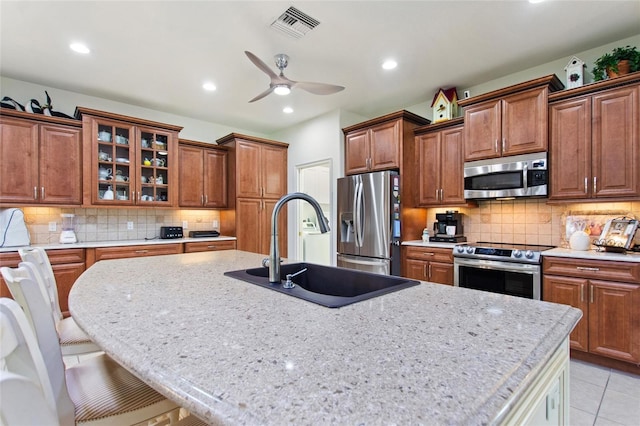 kitchen with backsplash, appliances with stainless steel finishes, sink, and light tile flooring