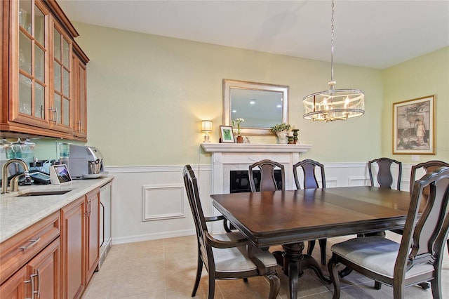 tiled dining space featuring a notable chandelier, sink, and a fireplace