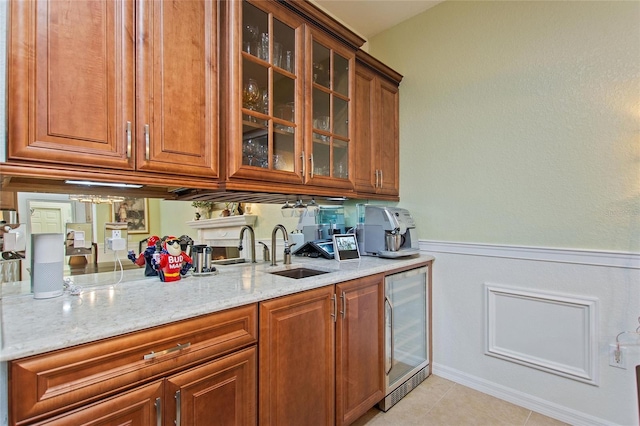 kitchen featuring sink, beverage cooler, light stone counters, and light tile flooring