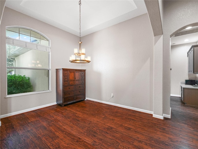 empty room with dark wood-type flooring and a chandelier