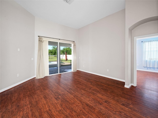 spare room featuring dark hardwood / wood-style floors and lofted ceiling