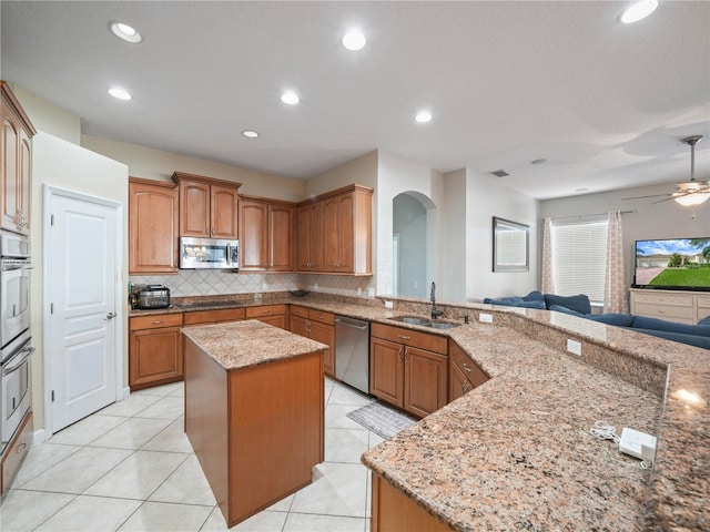 kitchen with ceiling fan, appliances with stainless steel finishes, sink, light tile floors, and a center island