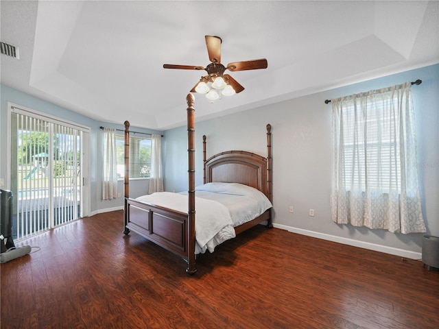 bedroom featuring ceiling fan, access to outside, dark hardwood / wood-style floors, and a tray ceiling