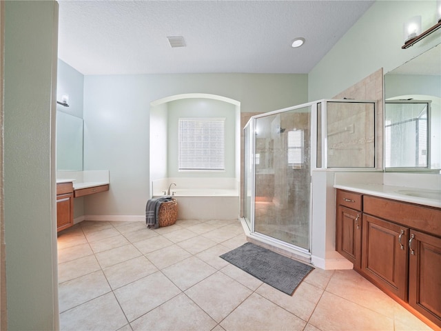 bathroom with a textured ceiling, tile flooring, plus walk in shower, and vanity