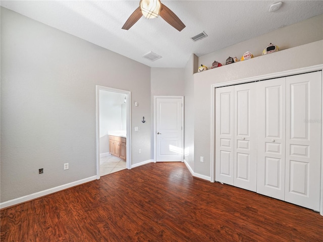 unfurnished bedroom featuring connected bathroom, dark hardwood / wood-style flooring, a textured ceiling, and ceiling fan