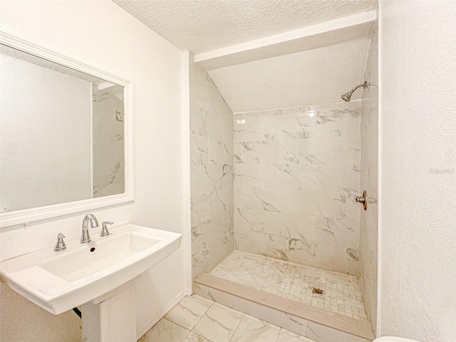 bathroom featuring lofted ceiling, tiled shower, and a textured ceiling