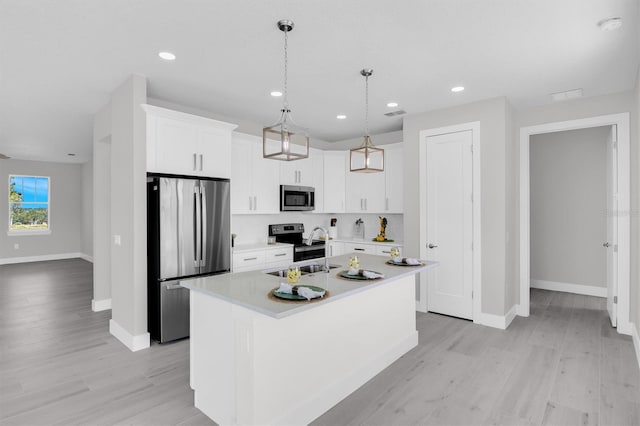 kitchen featuring pendant lighting, sink, stainless steel appliances, light hardwood / wood-style flooring, and a kitchen island with sink