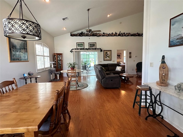 dining area featuring dark wood-type flooring, ceiling fan, and high vaulted ceiling