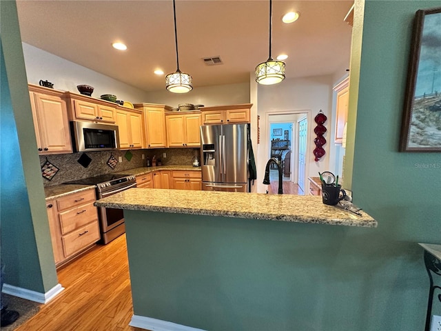 kitchen with pendant lighting, light stone countertops, light wood-type flooring, backsplash, and stainless steel appliances