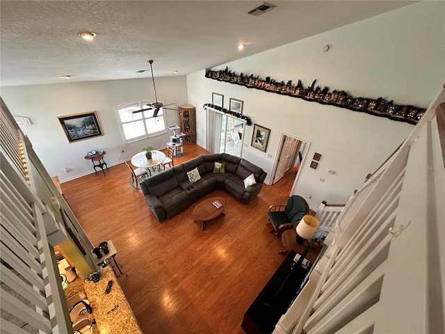 living room with a textured ceiling, high vaulted ceiling, ceiling fan, and hardwood / wood-style flooring