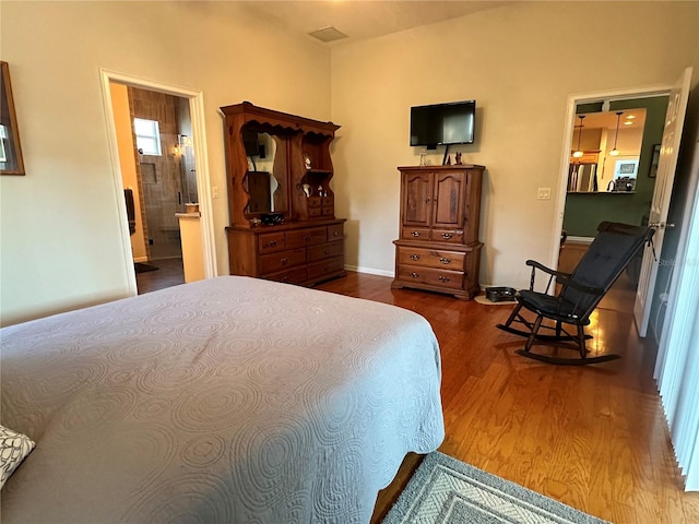 bedroom with dark hardwood / wood-style flooring and connected bathroom