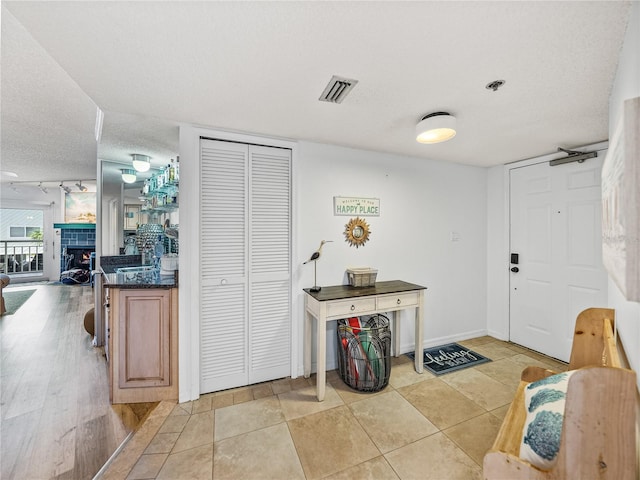 tiled entryway with rail lighting, a textured ceiling, and a tile fireplace