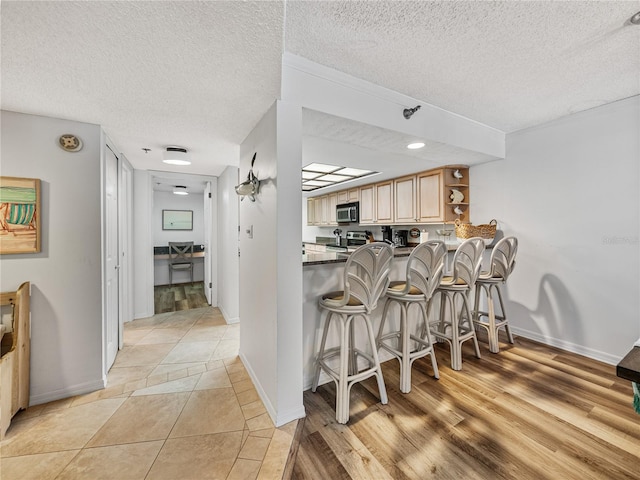 kitchen featuring light hardwood / wood-style floors, a breakfast bar area, and a textured ceiling