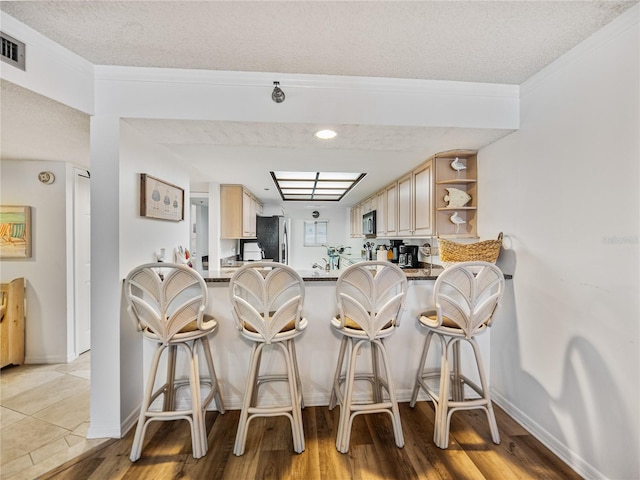 kitchen with a kitchen breakfast bar, light hardwood / wood-style floors, kitchen peninsula, and a textured ceiling