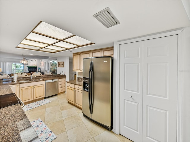 kitchen with appliances with stainless steel finishes, light brown cabinets, light tile floors, and hanging light fixtures