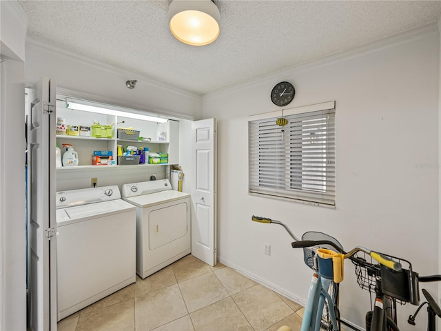 clothes washing area featuring a textured ceiling, ornamental molding, light tile floors, and washing machine and clothes dryer