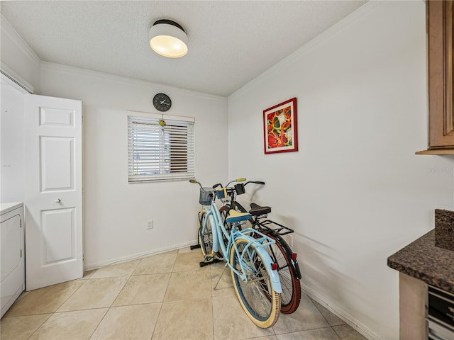 miscellaneous room with a textured ceiling, light tile flooring, crown molding, and washer / dryer