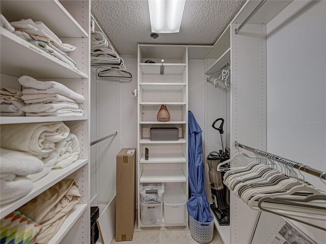 walk in closet with light tile flooring