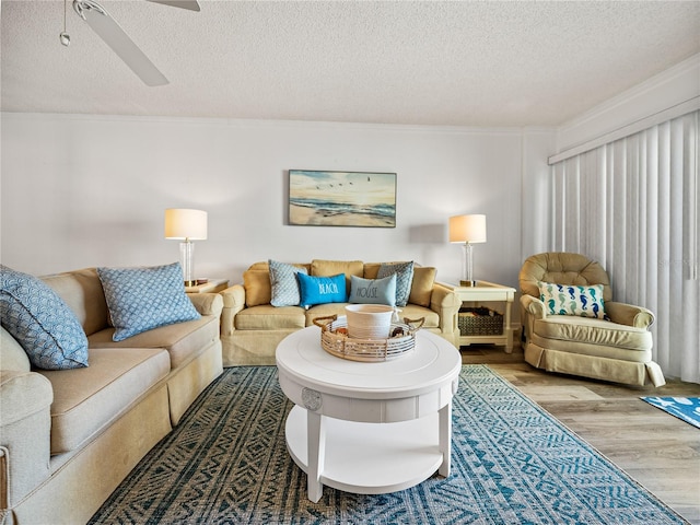 living room featuring light hardwood / wood-style floors, ceiling fan, and a textured ceiling