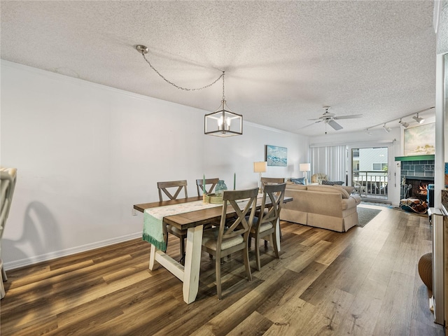 dining space with dark hardwood / wood-style floors, a textured ceiling, rail lighting, and a tiled fireplace