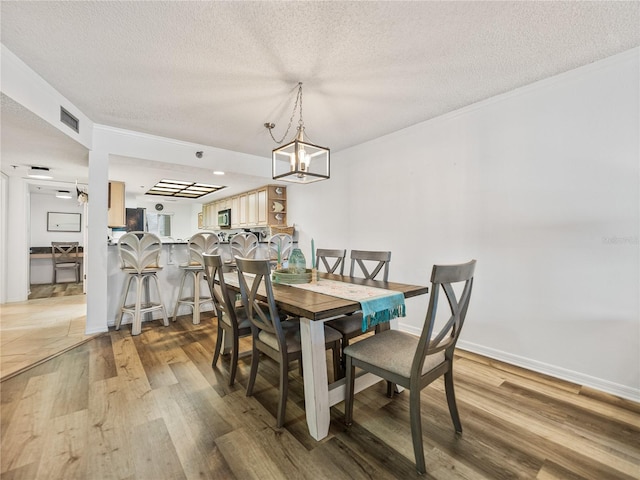 dining space with a notable chandelier, hardwood / wood-style flooring, and a textured ceiling