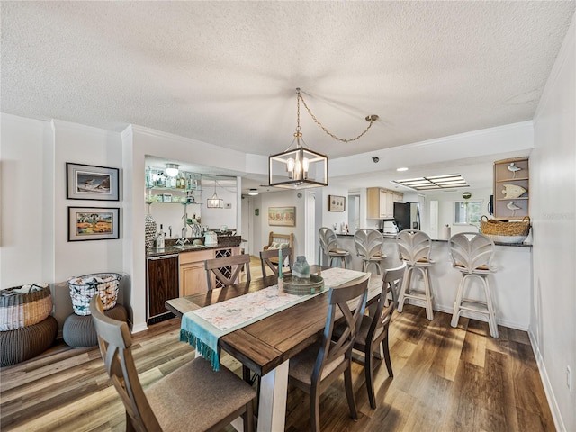 dining space featuring ornamental molding, wood-type flooring, and a textured ceiling