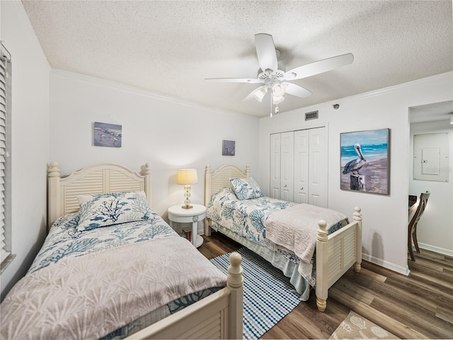 bedroom with ceiling fan, a textured ceiling, dark wood-type flooring, a closet, and ornamental molding