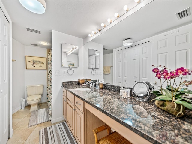 bathroom featuring tile flooring, vanity with extensive cabinet space, and toilet