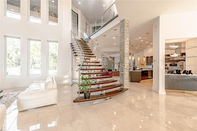 stairs featuring tile floors, decorative columns, and a high ceiling