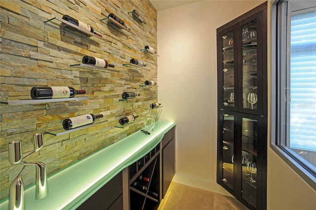 wine cellar featuring a healthy amount of sunlight, light tile floors, and bar area