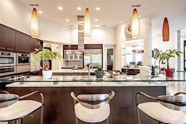 kitchen featuring a kitchen breakfast bar, tasteful backsplash, and light stone countertops