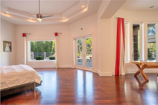 bedroom with ceiling fan, a raised ceiling, dark hardwood / wood-style flooring, and access to exterior