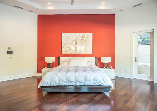 bedroom featuring a raised ceiling and dark hardwood / wood-style flooring