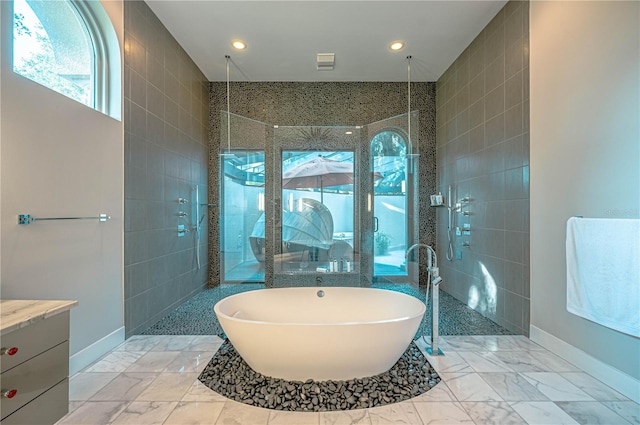 bathroom featuring independent shower and bath, vanity, tile floors, and tile walls