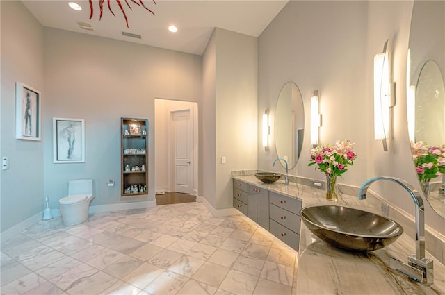 bathroom featuring tile flooring, dual vanity, toilet, and a high ceiling