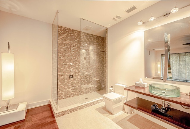 bathroom featuring tiled shower, vanity, hardwood / wood-style flooring, and toilet