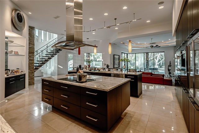 kitchen with dark brown cabinets, light tile floors, a kitchen island, and black electric cooktop