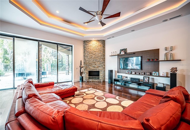 living room with a fireplace, a raised ceiling, ceiling fan, and hardwood / wood-style flooring