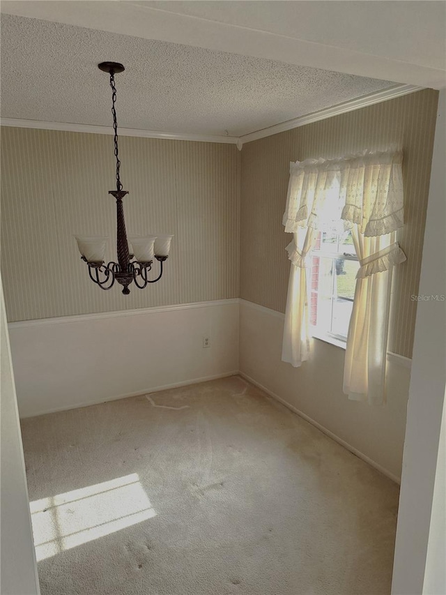 carpeted spare room with a notable chandelier, crown molding, and a textured ceiling