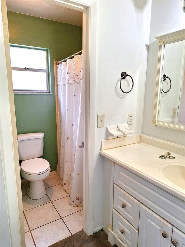 bathroom featuring tile flooring, vanity, and toilet