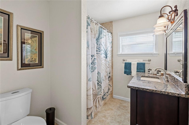 bathroom with tile floors, plenty of natural light, vanity, and toilet