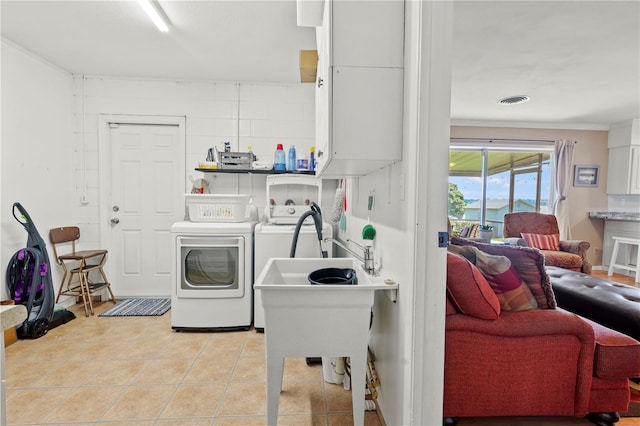 washroom featuring independent washer and dryer, crown molding, and light tile floors