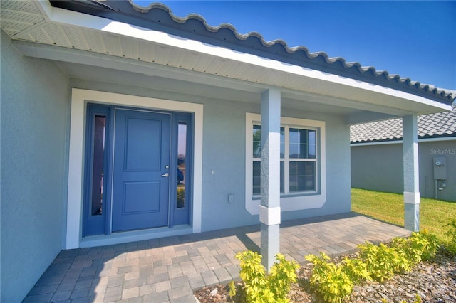 view of exterior entry with stucco siding and covered porch