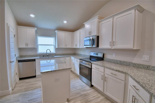 kitchen with recessed lighting, stainless steel appliances, a center island, a sink, and white cabinets