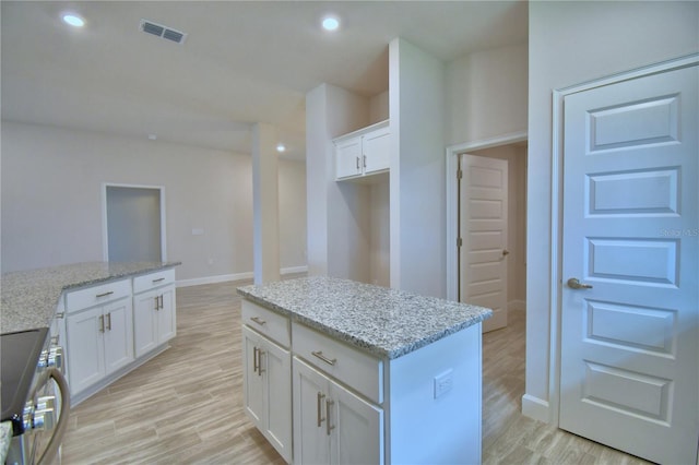 kitchen featuring visible vents, white cabinets, light wood-style floors, and stainless steel range