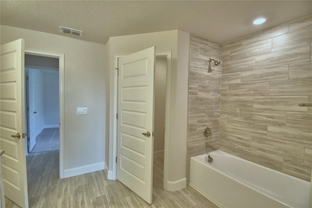 full bath featuring a textured ceiling, visible vents, baseboards, bathtub / shower combination, and wood finished floors