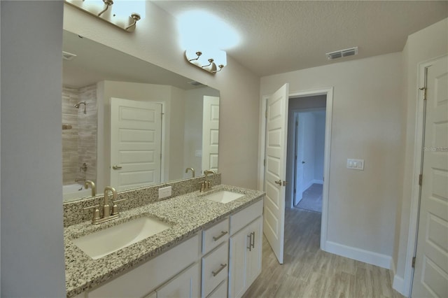 bathroom featuring double vanity, visible vents, a sink, and a textured ceiling